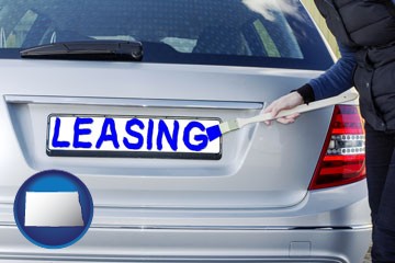 silver car with LEASING painted in blue - with North Dakota icon